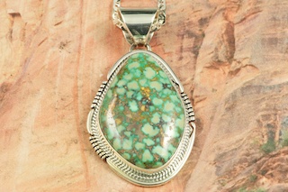 Genuine High Grade Kingman Web Turquoise set in Sterling Silver Pendant. Created by Navajo Artist John Nelson. Signed by the artist. The Mineral Park Mine, in the Cerbat Mountains 14 miles northwest of Kingman, was first mined by Indians centuries before white man came to the area. It is one of the three sites of prehistoric mining localities in the state of Arizona. Mineral Park was the most extensively worked area by the Indians of the three. S.A. �Chuck� Colbaugh found a cache of stone hammers uncovered in ancient trenches and tunnels, when he had the turquoise mining concession in May of 1962. Ithaca Peak and Turquoise Mine (formally called Aztec Mountain or Aztec Peak) are the most famous of the peaks in the area containing turquoise. Free 18